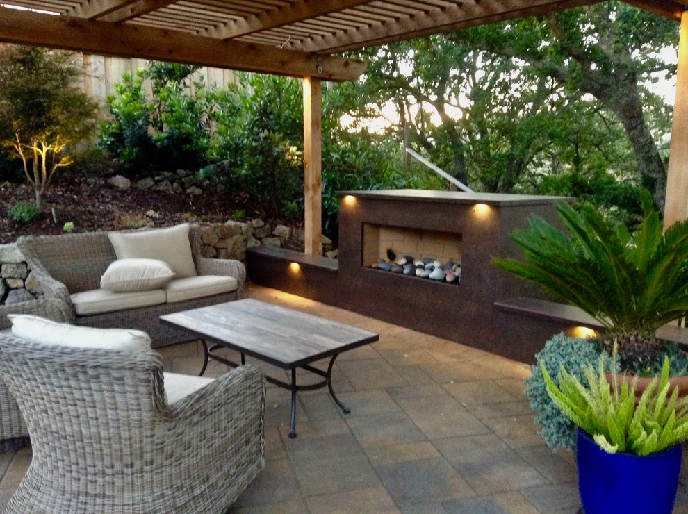 Exemple d'une terrasse arrière tendance de taille moyenne avec un foyer extérieur, une pergola et des pavés en béton.