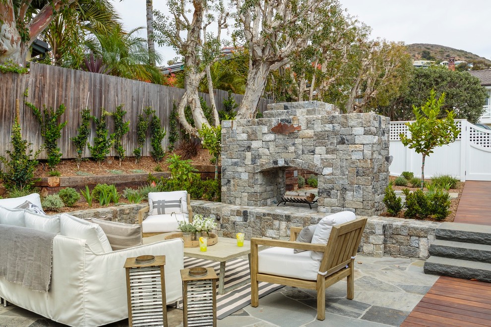 Design ideas for a coastal back patio in Orange County with a fireplace and no cover.