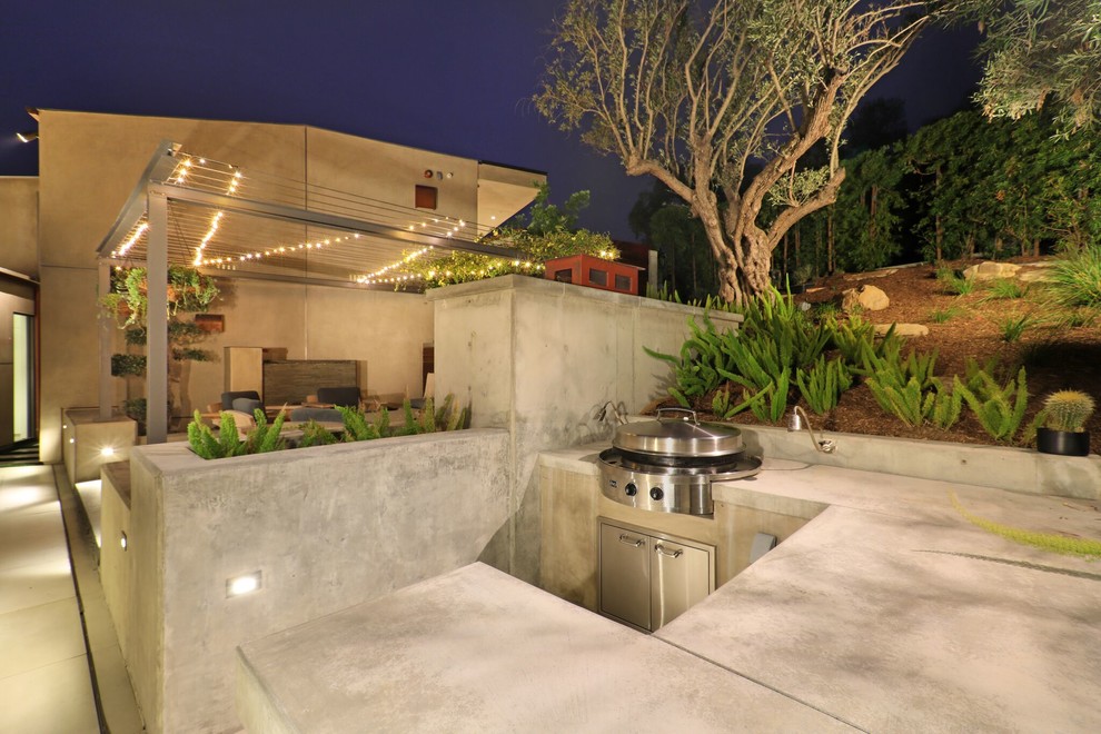 Réalisation d'une très grande terrasse arrière design avec une cuisine d'été, des pavés en béton et aucune couverture.