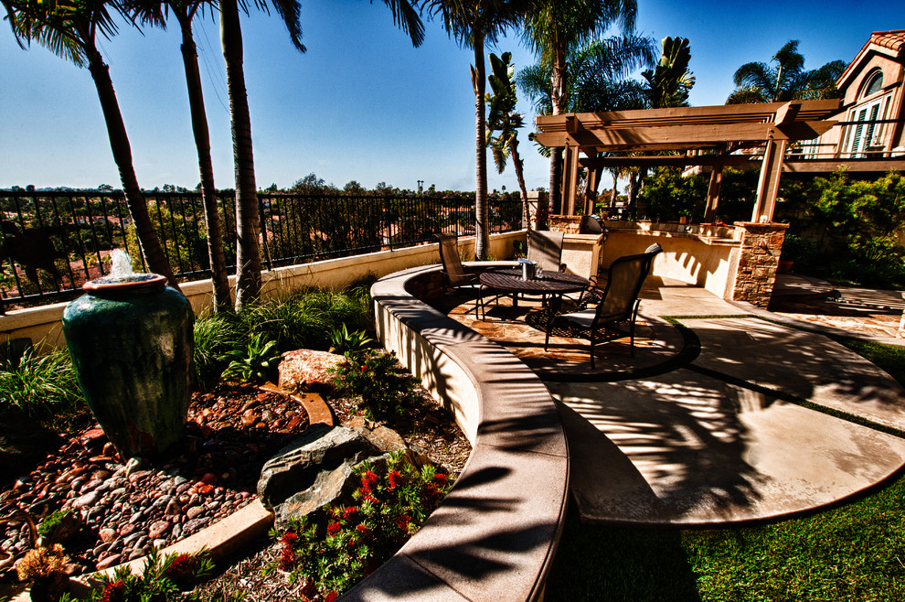 Inspiration for a mid-sized mediterranean backyard concrete patio kitchen remodel in Orange County with a pergola