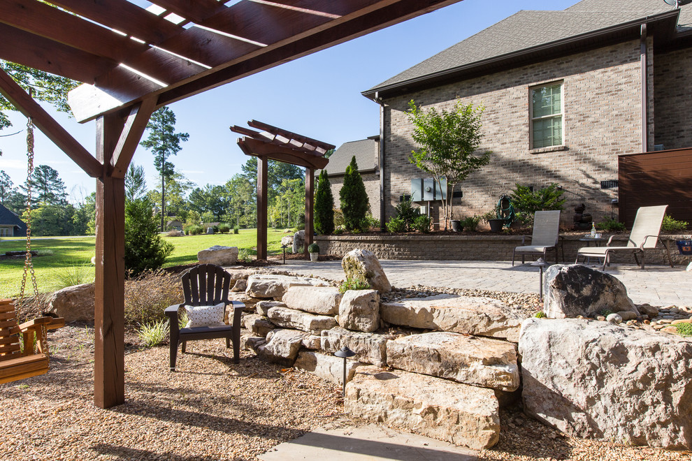 Réalisation d'une terrasse arrière chalet avec des pavés en béton et une pergola.