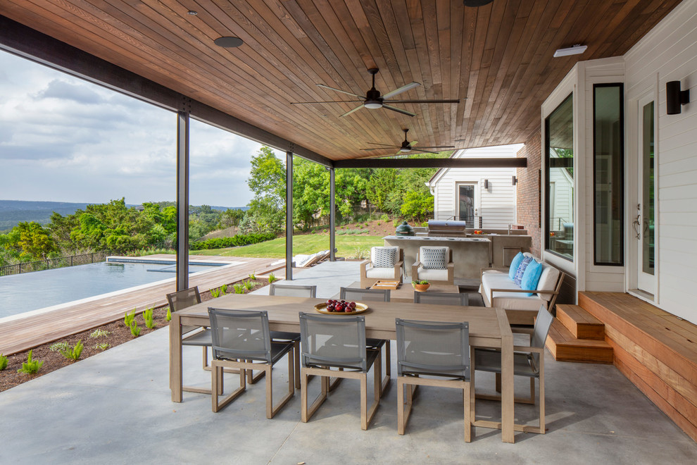 Design ideas for a large contemporary back patio in Austin with an outdoor kitchen, an awning and concrete slabs.