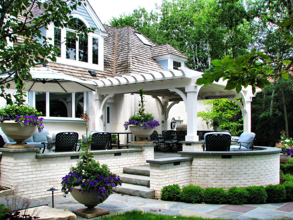 Immagine di un patio o portico tradizionale dietro casa con pavimentazioni in pietra naturale e una pergola