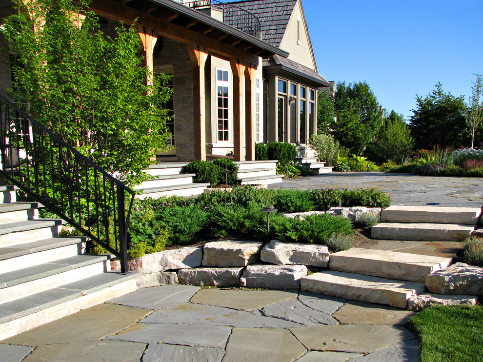 Cette photo montre une terrasse arrière chic avec des pavés en pierre naturelle et une extension de toiture.