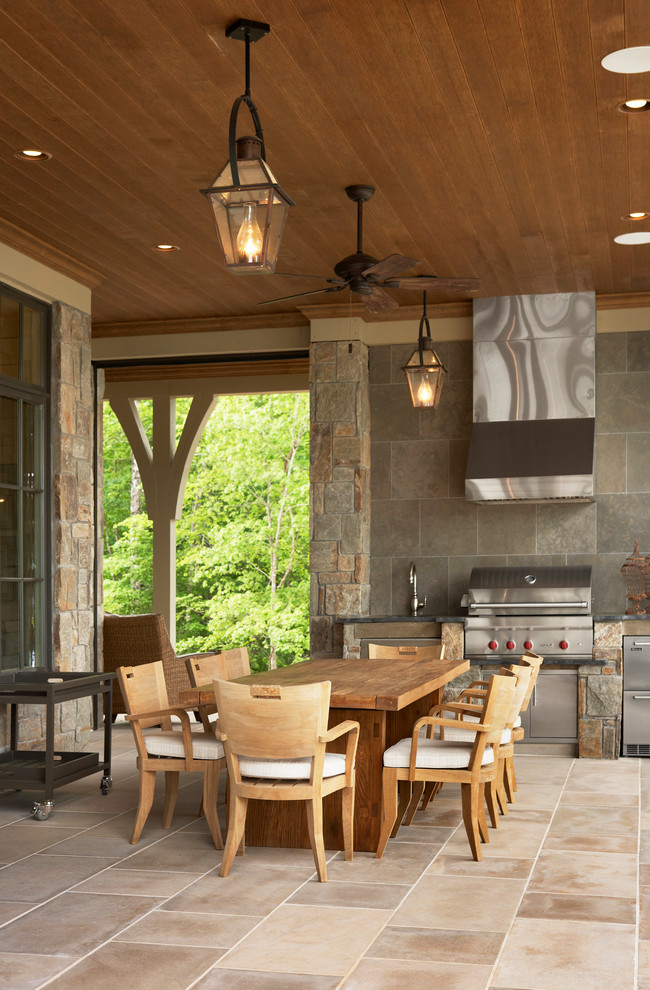 Idee per un grande patio o portico chic dietro casa con pavimentazioni in pietra naturale e un tetto a sbalzo