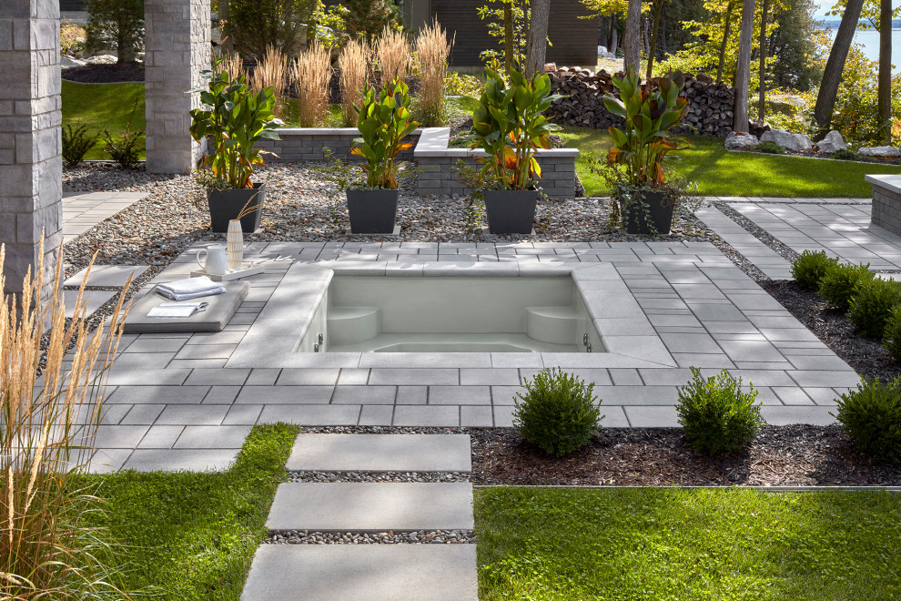Minimalist backyard concrete paver patio photo in Montreal with a fire pit
