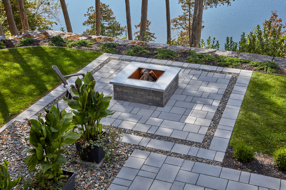 Example of a minimalist backyard concrete paver patio design in Montreal with a fire pit