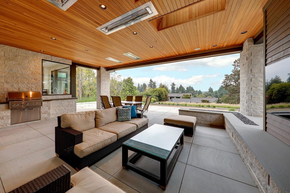 Cette photo montre une grande terrasse arrière tendance avec un foyer extérieur, des pavés en béton et une extension de toiture.
