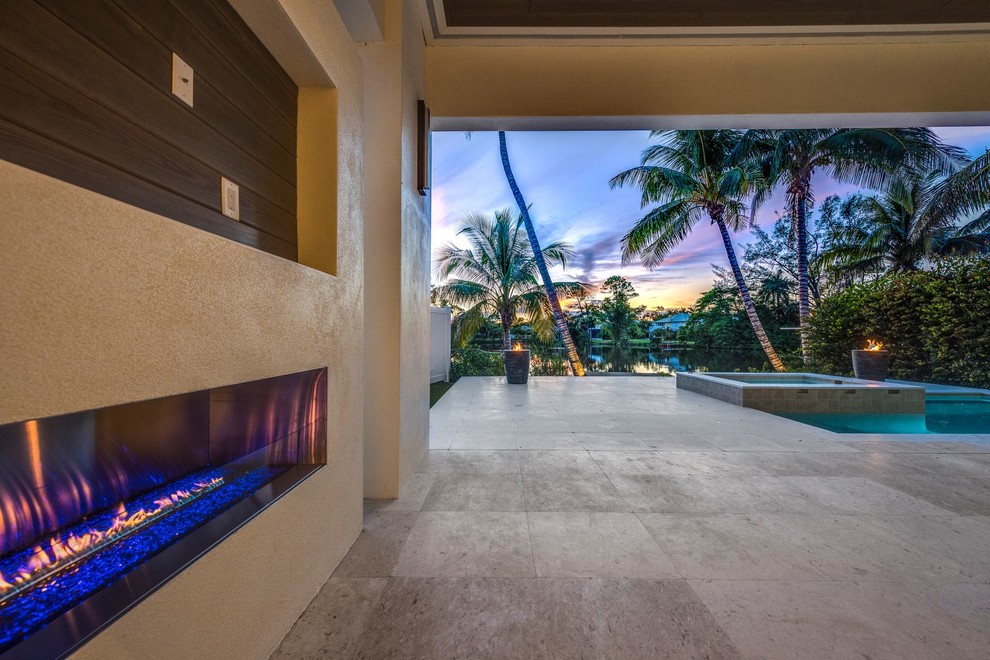 Design ideas for a contemporary back patio in Miami with a fire feature and natural stone paving.