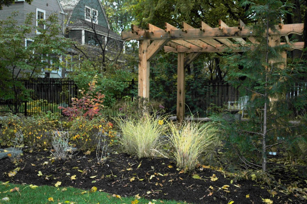 Ejemplo de patio de estilo americano de tamaño medio en patio trasero con adoquines de piedra natural y pérgola