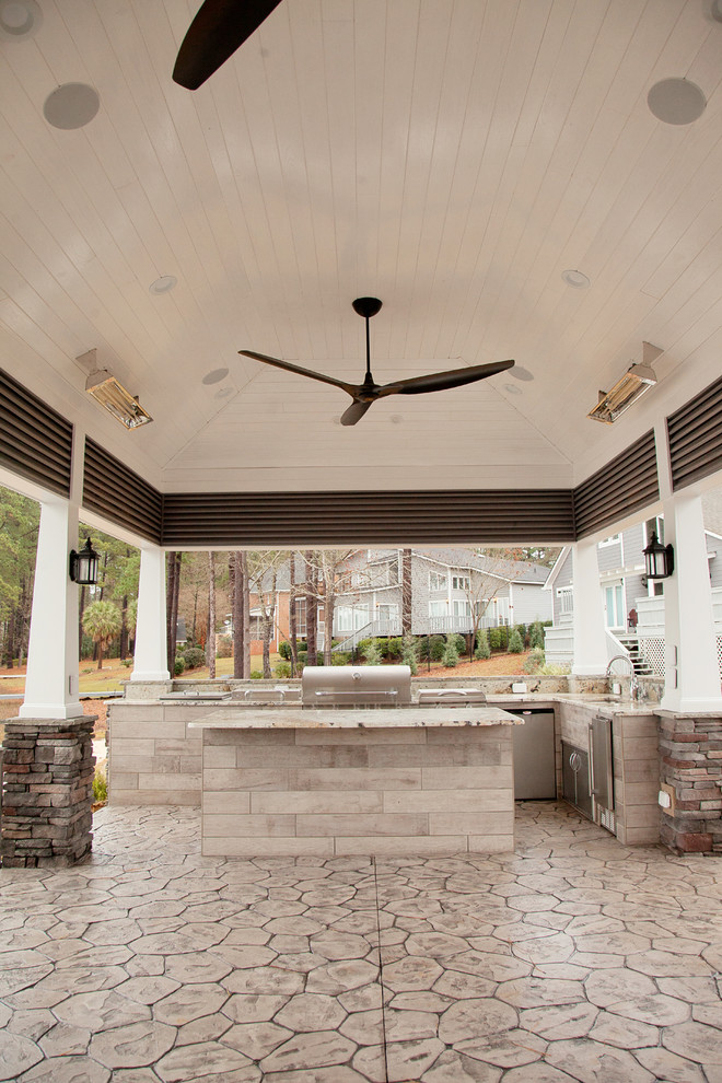 Immagine di un patio o portico stile rurale di medie dimensioni e dietro casa con un focolare, un tetto a sbalzo e cemento stampato