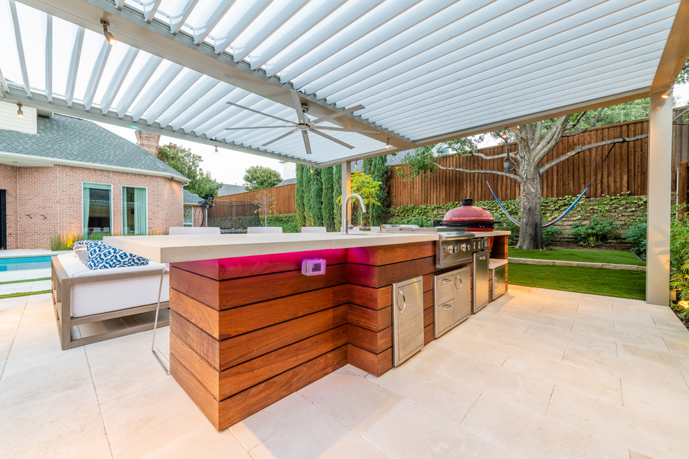 Cette image montre une terrasse arrière minimaliste de taille moyenne avec une cuisine d'été, des pavés en pierre naturelle et une pergola.
