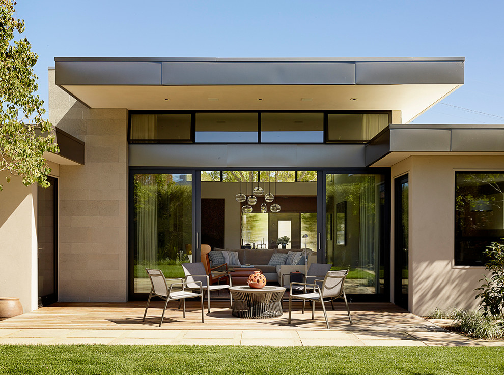 Cette image montre une terrasse design avec une extension de toiture.