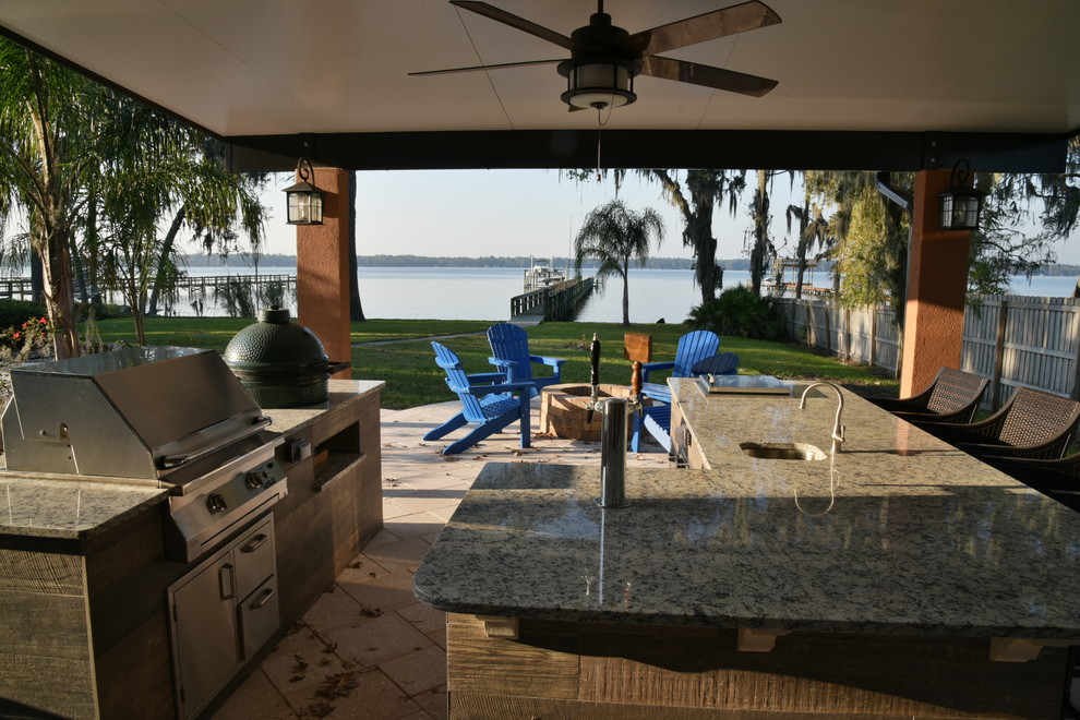 This is an example of a large contemporary back patio in Jacksonville with an outdoor kitchen, natural stone paving and a roof extension.