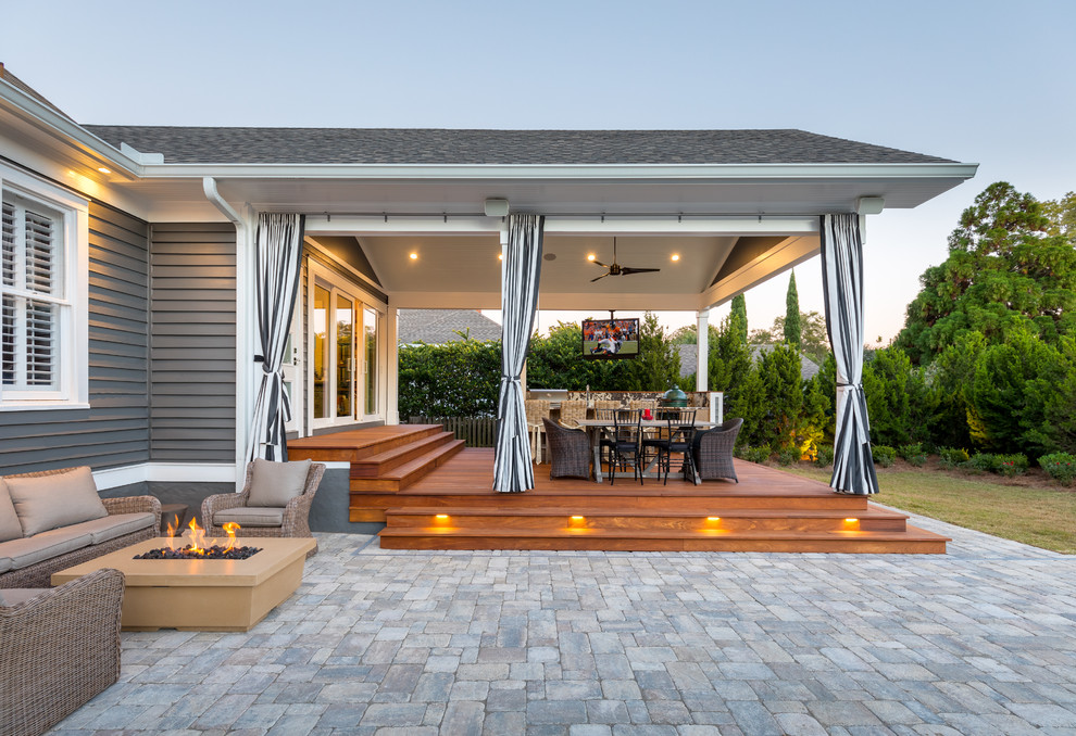 Aménagement d'une grande terrasse arrière classique avec une cuisine d'été, des pavés en béton et une extension de toiture.