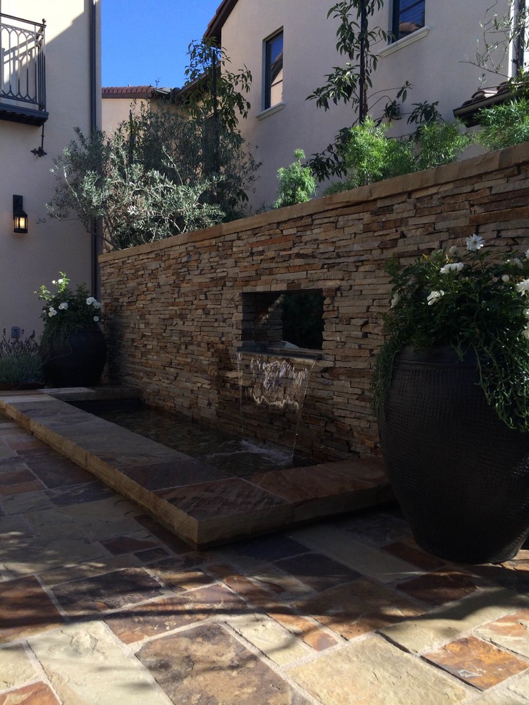 Foto de patio rural de tamaño medio sin cubierta en patio trasero con fuente y adoquines de piedra natural