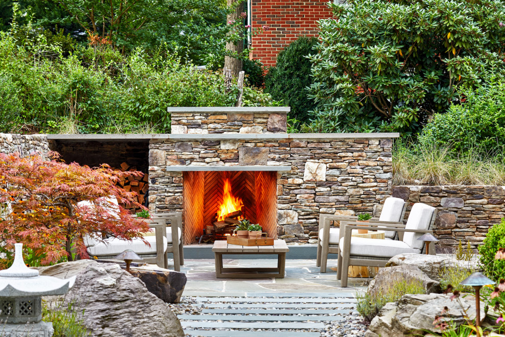 Imagen de patio tradicional renovado grande sin cubierta en patio trasero con chimenea y adoquines de piedra natural