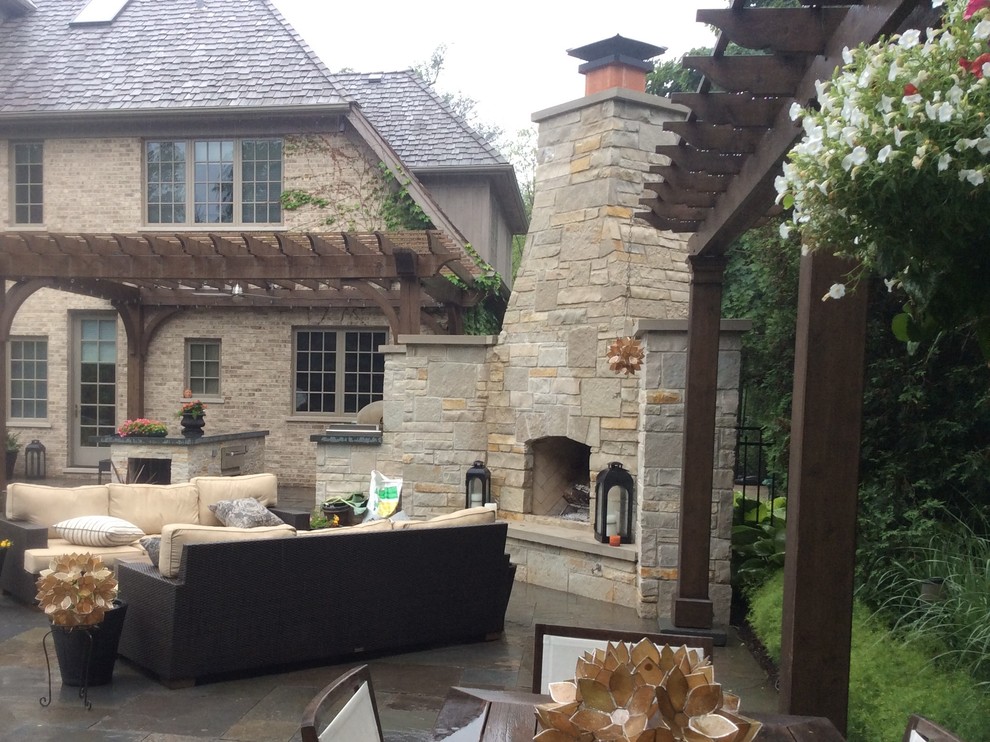 Exemple d'une grande terrasse arrière chic avec un foyer extérieur, des pavés en pierre naturelle et aucune couverture.