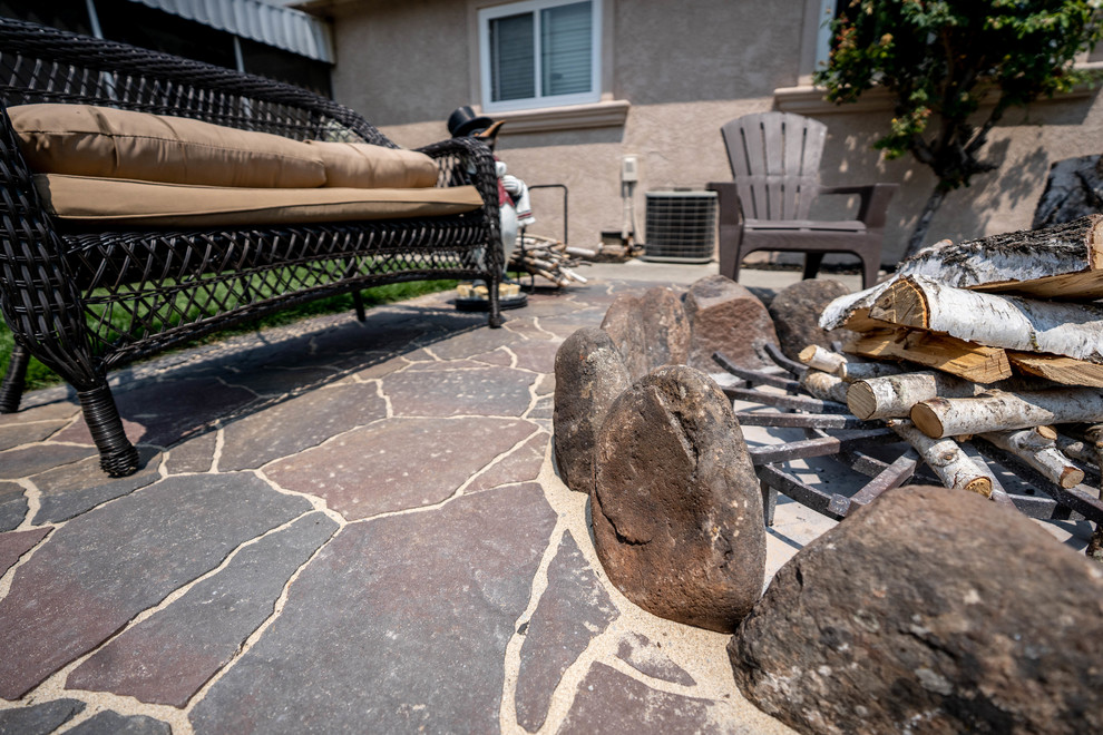 Ejemplo de patio tradicional pequeño sin cubierta en patio trasero con chimenea y adoquines de piedra natural