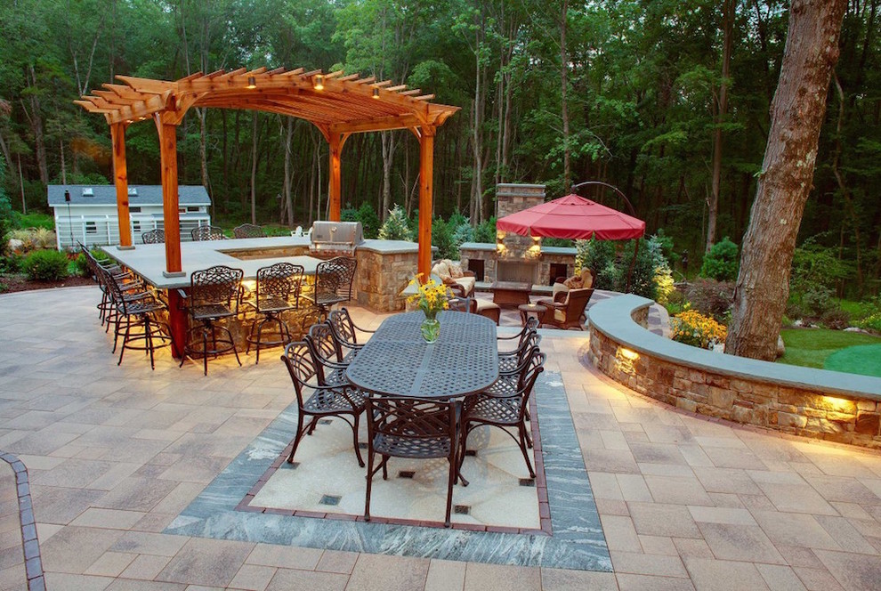 Exemple d'une terrasse arrière chic avec une cuisine d'été, des pavés en brique et une pergola.