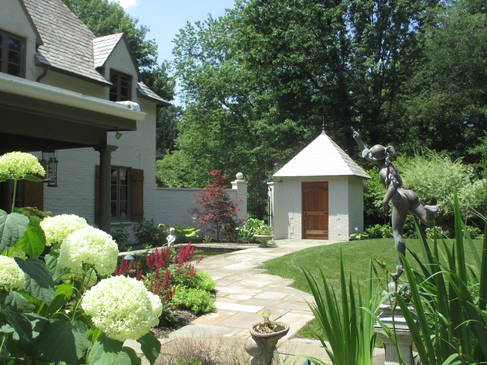 Ejemplo de patio tradicional renovado de tamaño medio sin cubierta en patio trasero con adoquines de piedra natural