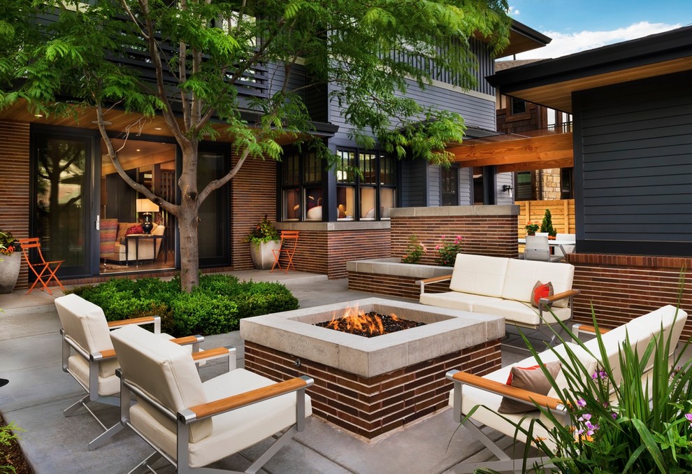 Foto de patio contemporáneo de tamaño medio sin cubierta en patio trasero con brasero y losas de hormigón