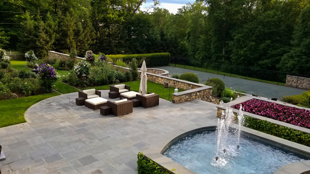 Inspiration for a large classic back patio in New York with a water feature, natural stone paving and no cover.