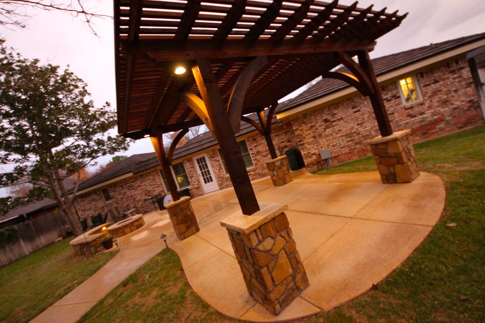 Immagine di un patio o portico di medie dimensioni e dietro casa con un focolare, lastre di cemento e una pergola