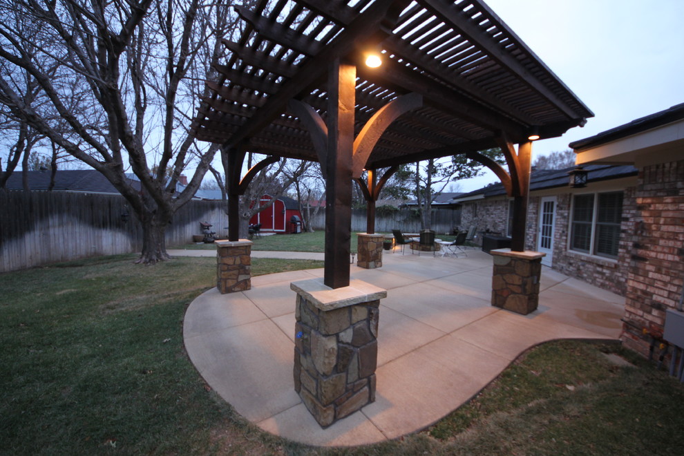 Idee per un patio o portico rustico di medie dimensioni e dietro casa con un focolare, lastre di cemento e una pergola