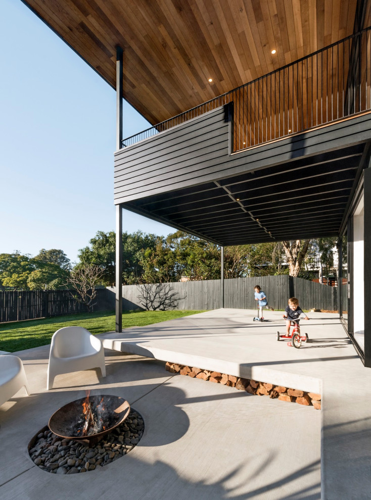 Réalisation d'une terrasse arrière design avec un foyer extérieur.