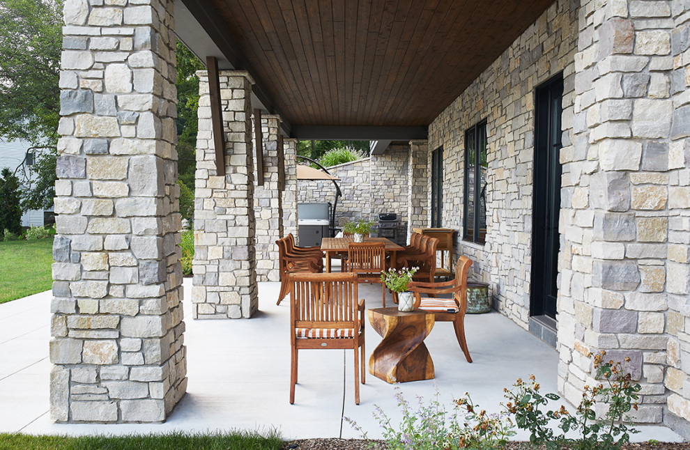 Immagine di un patio o portico chic dietro casa con lastre di cemento e un tetto a sbalzo