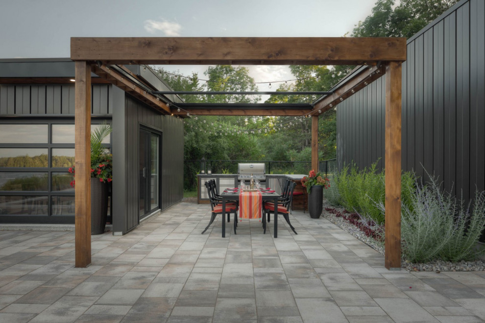Imagen de patio minimalista grande en patio trasero con cocina exterior, adoquines de piedra natural y pérgola