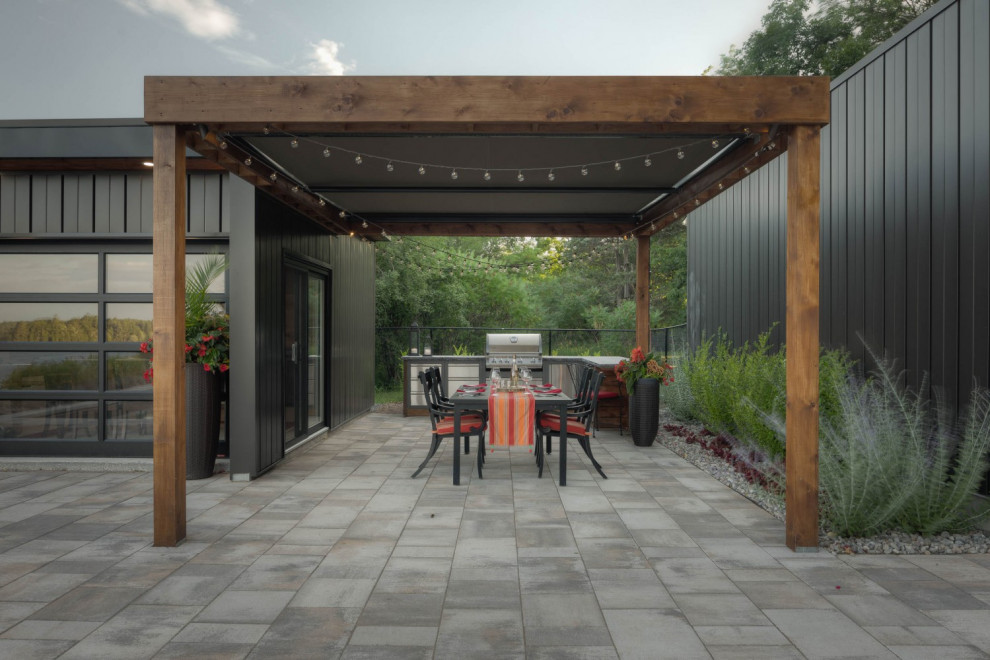 Ejemplo de patio minimalista grande en patio trasero con cocina exterior, adoquines de piedra natural y toldo