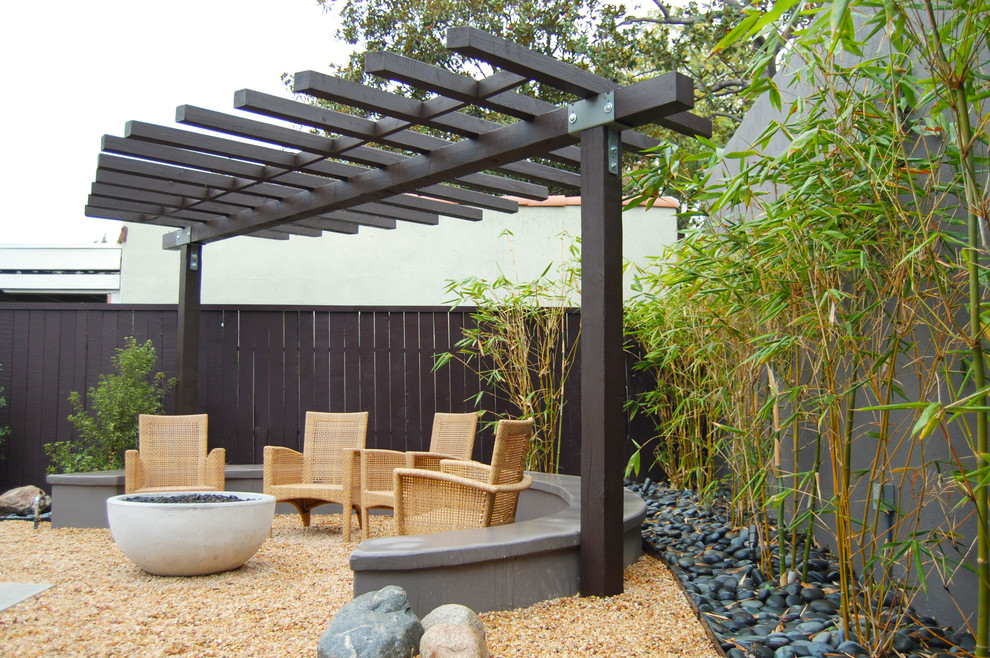 Diseño de patio de estilo zen de tamaño medio en patio trasero con brasero y gravilla