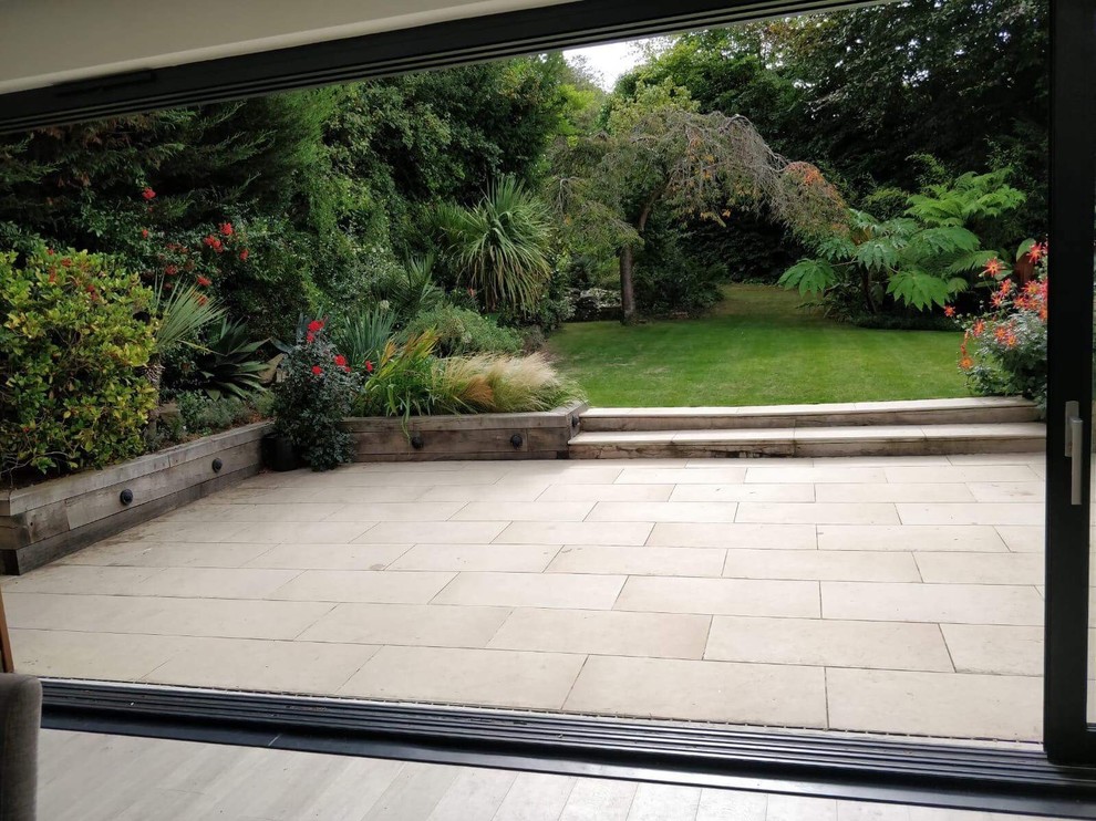 Large porcelain patio, oak sleeper retaining walls and new lawn in