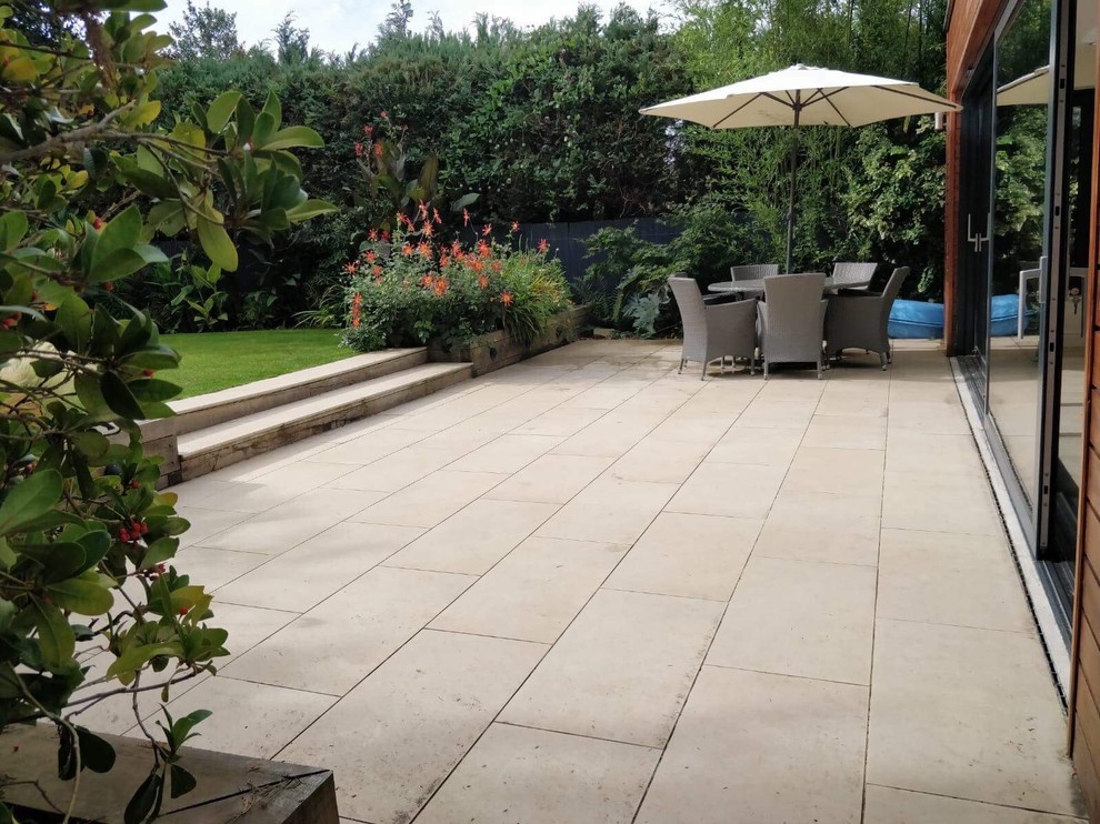 Large porcelain patio, oak sleeper retaining walls and new lawn in