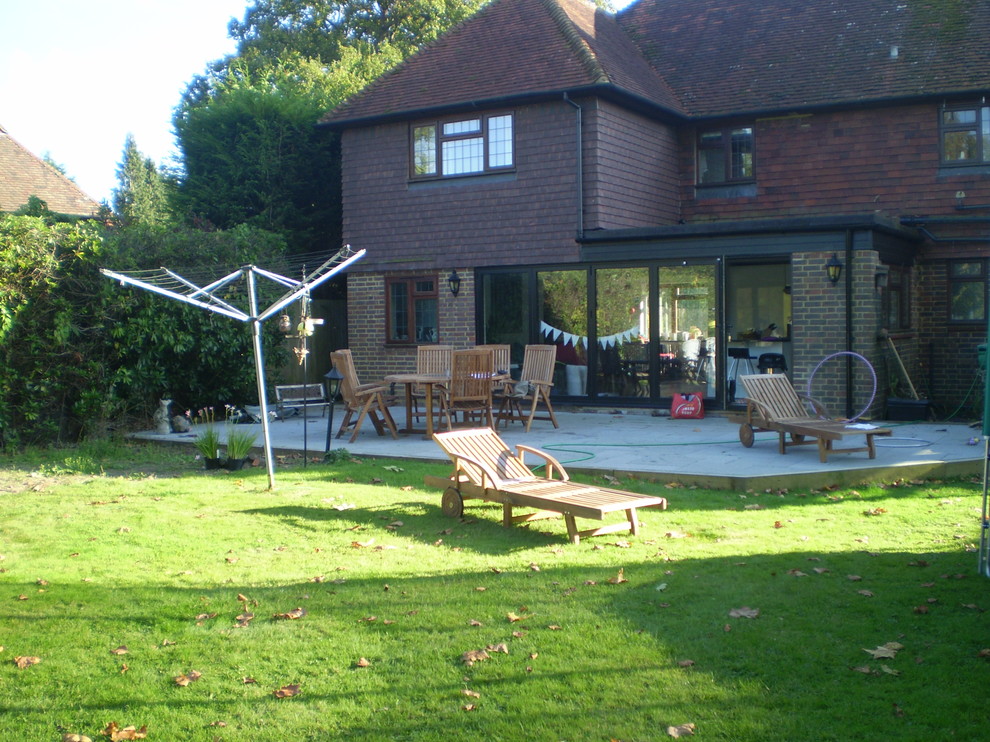 Inspiration for a large farmhouse back patio in Sussex with concrete paving and no cover.