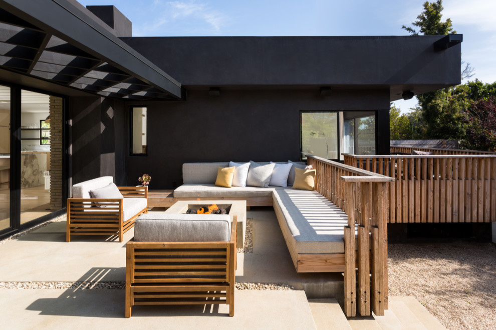 Cette photo montre une terrasse arrière tendance de taille moyenne avec un foyer extérieur, une dalle de béton et aucune couverture.