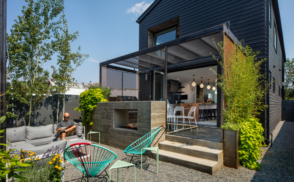 Réalisation d'une terrasse arrière minimaliste de taille moyenne avec un foyer extérieur, une dalle de béton et une pergola.
