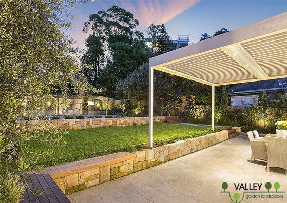 Large contemporary back patio in Sydney with natural stone paving and a pergola.