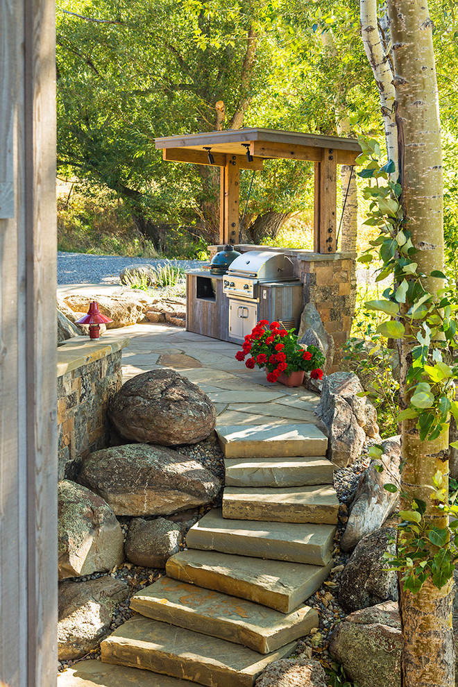 На фото: двор в стиле рустика с покрытием из каменной брусчатки и зоной барбекю с