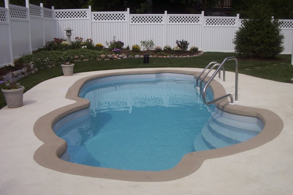 Esempio di un'ampia piscina tropicale con lastre di cemento