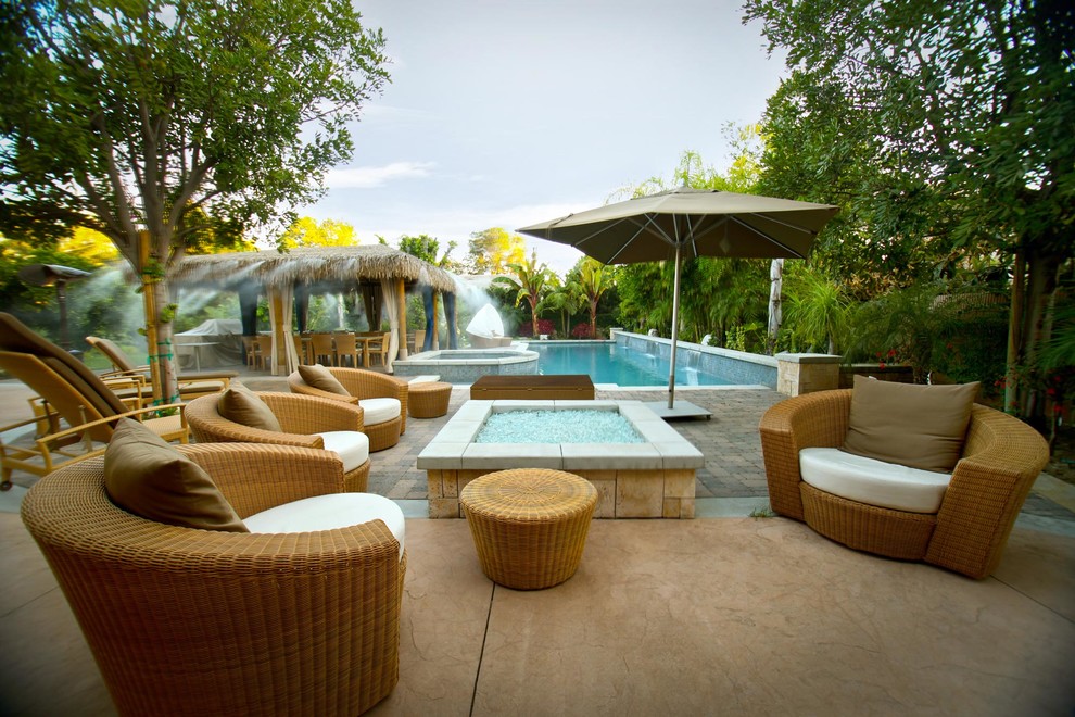 Photo of a large world-inspired back patio in Los Angeles with a fire feature, concrete slabs and no cover.