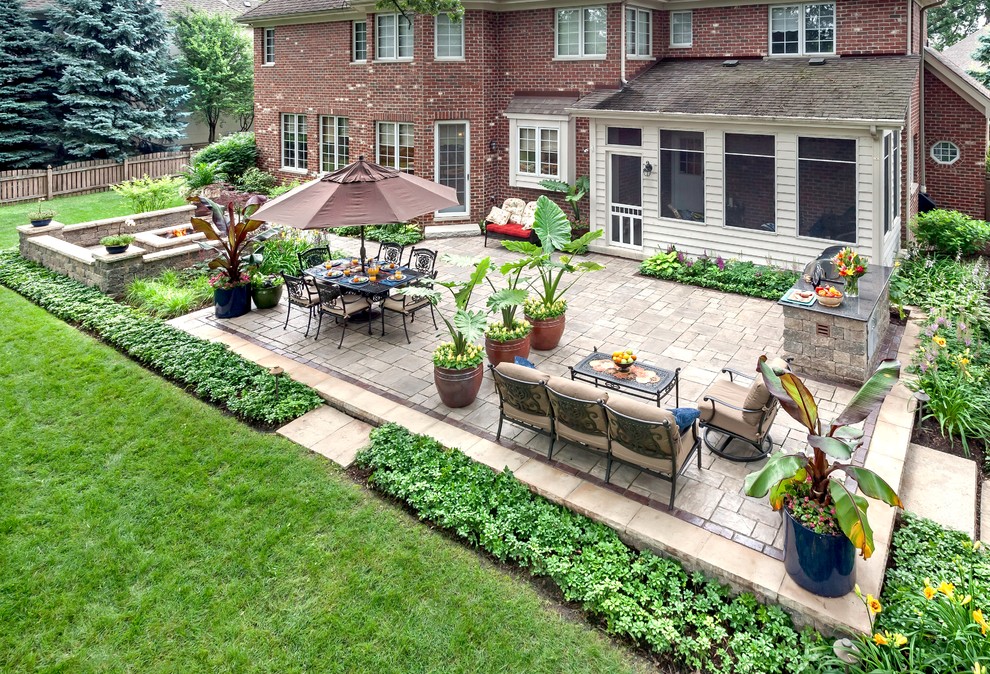 This is an example of a large classic back patio in Chicago with a fire feature, no cover and brick paving.