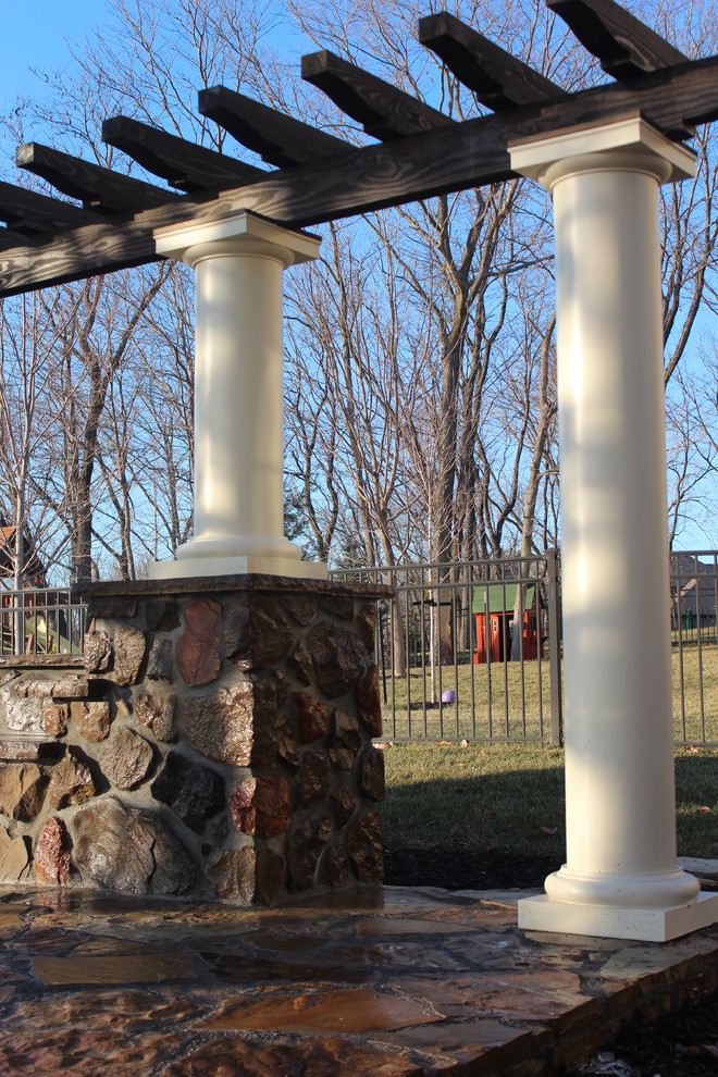 Immagine di un patio o portico design dietro casa con un focolare, cemento stampato e una pergola