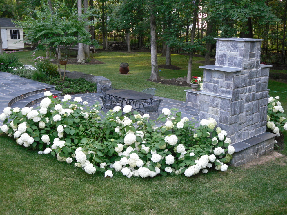 Imagen de jardín tradicional grande en patio trasero con brasero y adoquines de piedra natural