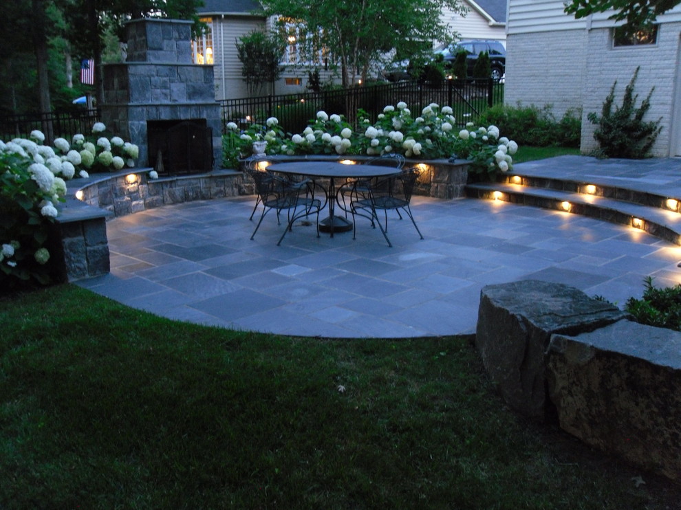 Large classic back patio in DC Metro with no cover, a fire feature and natural stone paving.