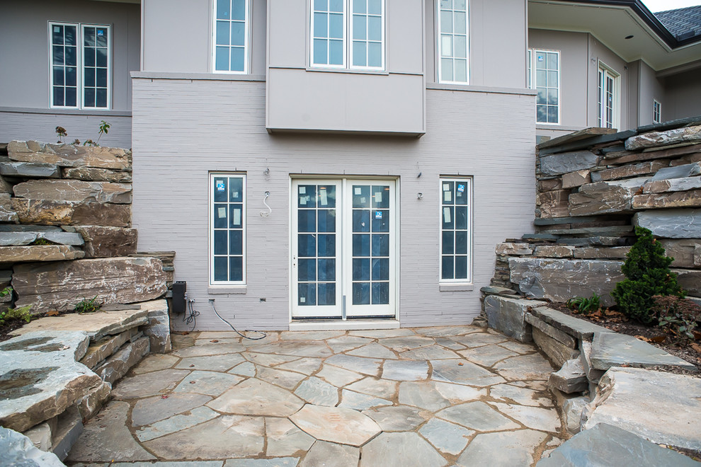 Immagine di un grande patio o portico eclettico dietro casa con pavimentazioni in pietra naturale e nessuna copertura
