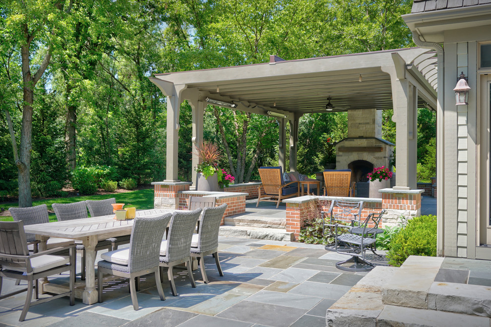 Foto de patio de estilo de casa de campo grande en patio trasero con chimenea, adoquines de piedra natural y pérgola