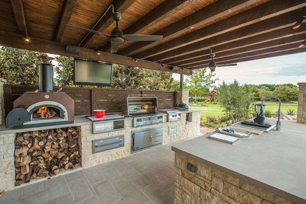 Large elegant backyard stone patio kitchen photo in Dallas with a roof extension